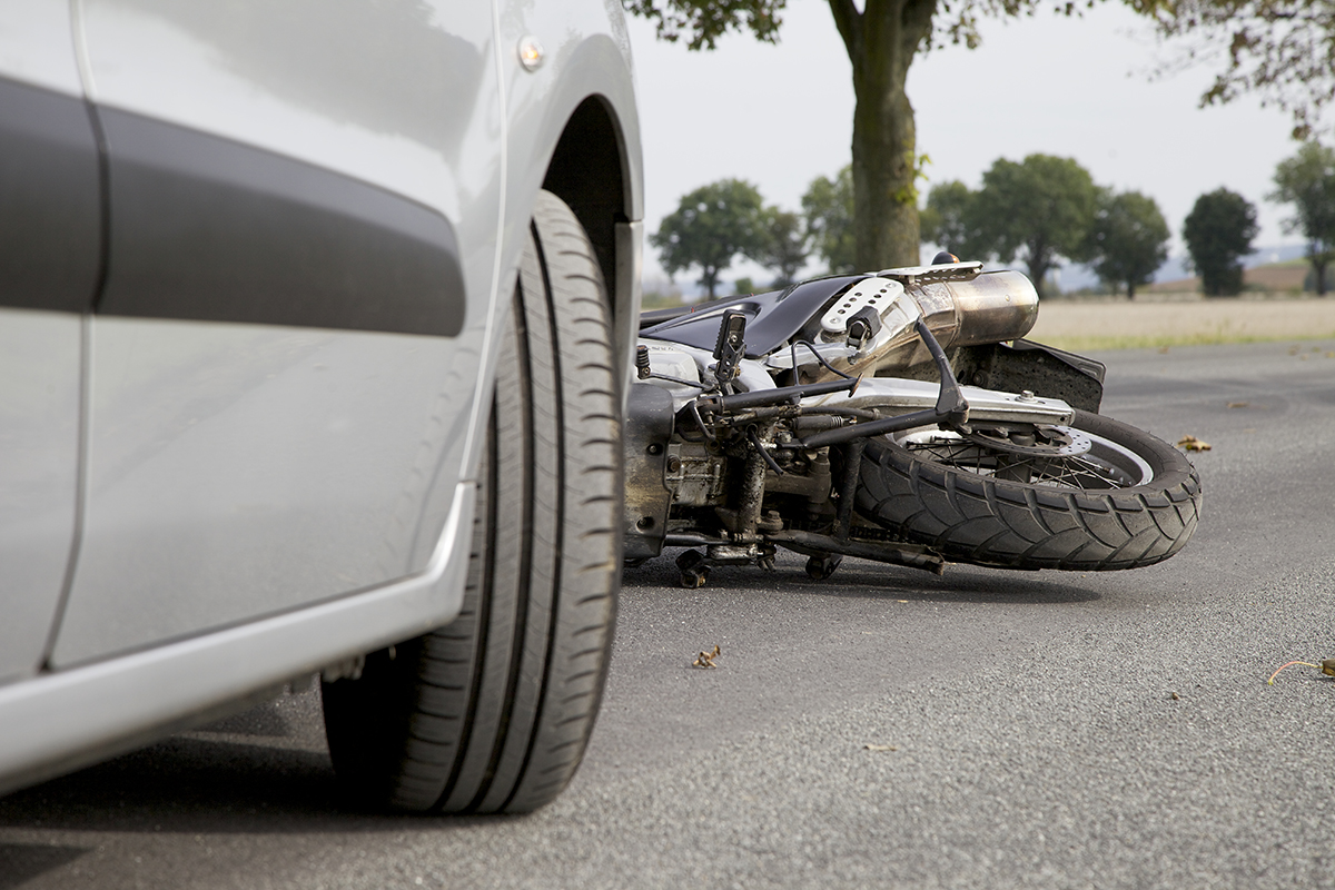 accidente de tráfico en el que hay un coche y una moto tirada en el suelo. foto de reclamador.es